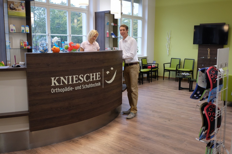 Herr Kniesche steht mit einer Mitarbeiterin am Tresen im Empfangsbereichs im Laden.