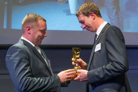 Henry Kiesche empfängt den Pokal "Zukunftspreis Brandenburg" von einem Jury Mitglied.