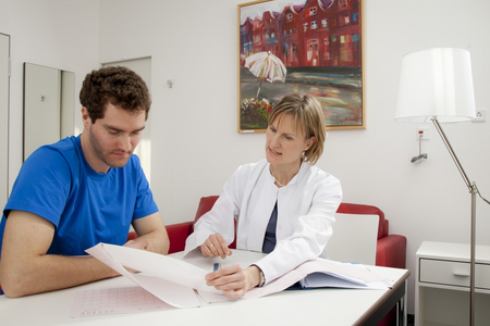 Ärztin und Patient sitzen gemeinsam an einem Tisch und besprechen die Ergebnisse des Checkups.