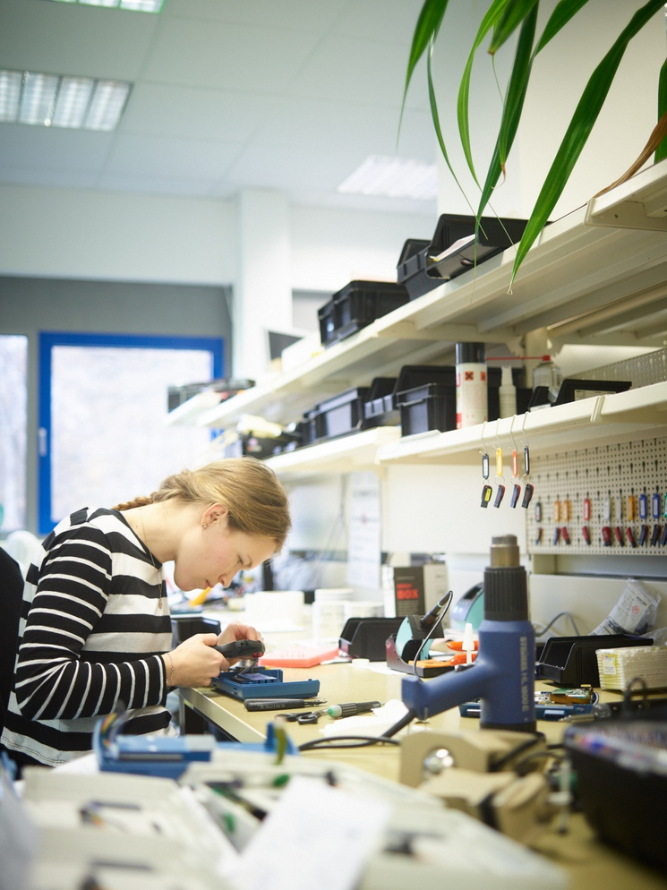 Eine junge Medizintechnikerin arbeitet mit Spezialwerkzeug in einem Labor.