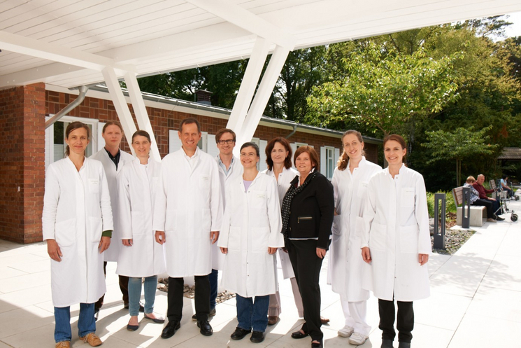 Aufnahme des zehnköpfigen Ärzte Teams in weißen Kitteln vor dem Klinikgebäude